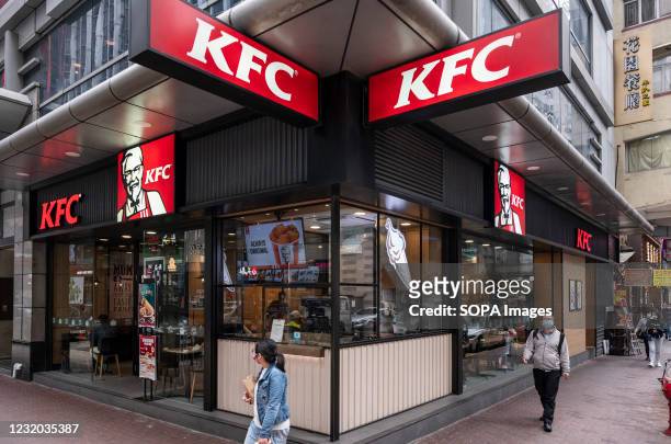 Pedestrians walk past an American fast food chicken restaurant chain, Kentucky Fried Chicken and logo seen in Hong Kong.