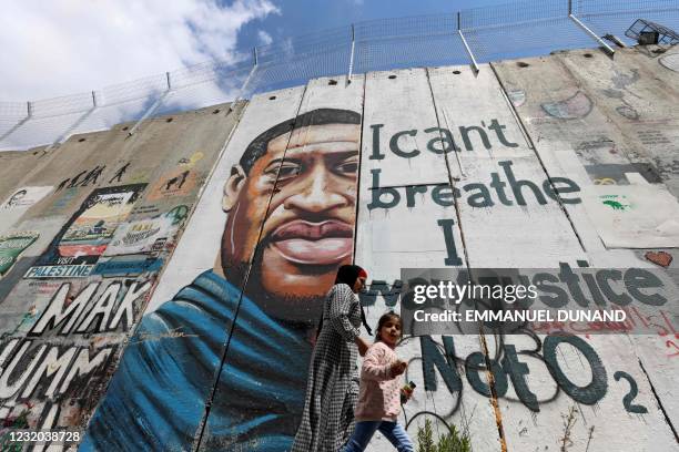 People walk past a mural showing the face of George Floyd, an unarmed handcuffed black man who died after a white policeman knelt on his neck during...