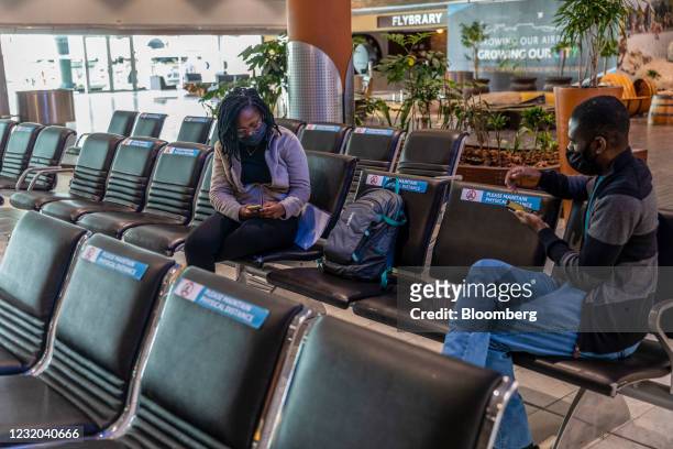 Travelers sit at social distance to each other at a gate in the departures terminal at Cape Town International Airport in Cape Town, South Africa, on...