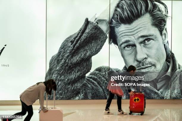 Children run past a large commercial ad of Italian luxury tailor fashion brand Brioni brand displaying its brand ambassador the American actor Brad...