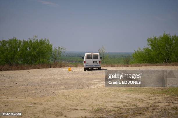 In a photo taken on March 27, 2021 a border patrol van sits parked next to a bucket of water before the skyline of Mexico in the southern Texas...