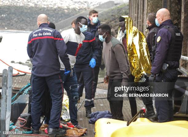 French firemen and policemen surround migrants who disembark a boat after they were rescued when their makeshift boat encountered difficulties during...