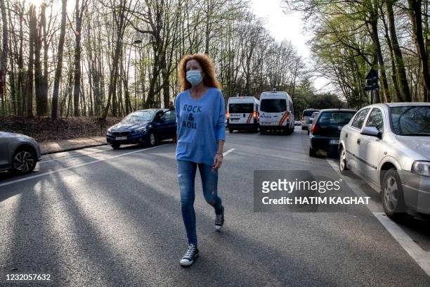 An unidentified woman wearing a shirt that reads 'Rock and Roll' walks away from police vans in the Bois de La Cambre - Ter Kamerenbos, in Brussels,...