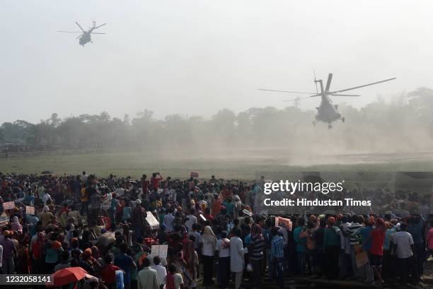 Crowd looks at PM Narendra Modi leave in a helicopter after a public rally for West Bengal Assembly Elections, at Jaynagar, in South 24 Parganas, on...