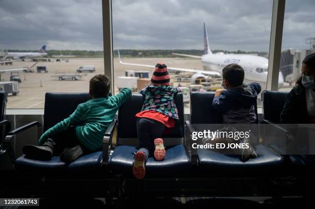 Siblings Dariel ]and Diana from Honduras sit with Daniel from El Salvador at Houston airport during a translfer on March 30, 2021 after being...