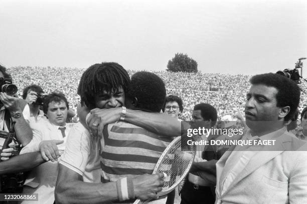 French tennis player Yannick Noah embraces his father Zacharie Noah on the tennis court after winning the Rolland Garros tennis tournament by...