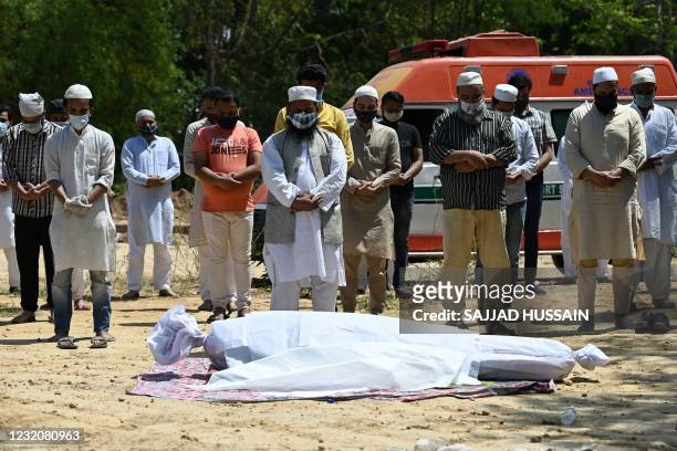 Relatives and friends offer a prayer during the funeral of a Covid-19 coronavirus victim at a graveyard in New Delhi on April 3, 2021.