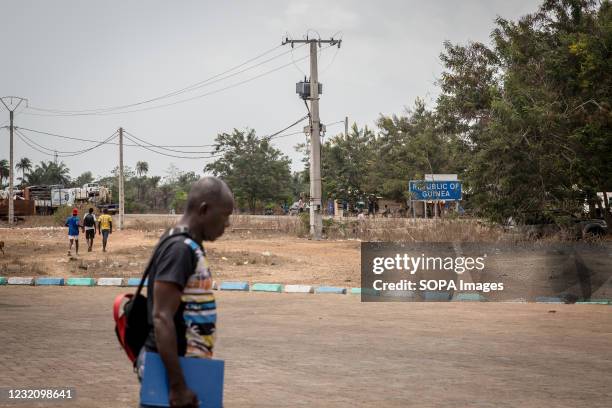 Man walks past a sign for the Republic of Guinea, which marks the border with Sierra Leone. The latest Ebola outbreak in Guinea was declared in...