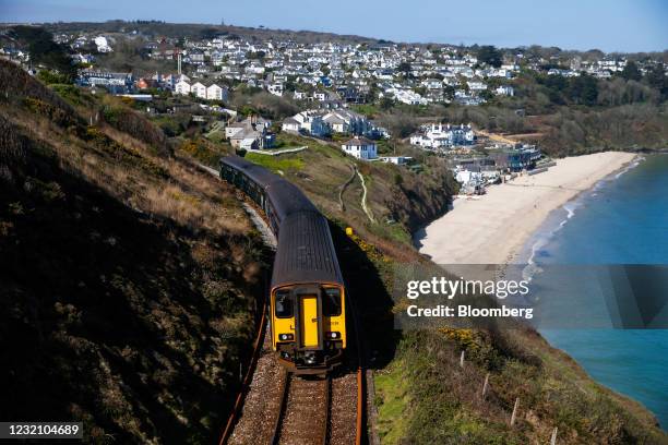 Passenger railway train passes along the coastline in view of Carbis Bay Hotel & Estate in Cornwall, U.K., on Sunday, April 4, 2021. U.K. Prime...