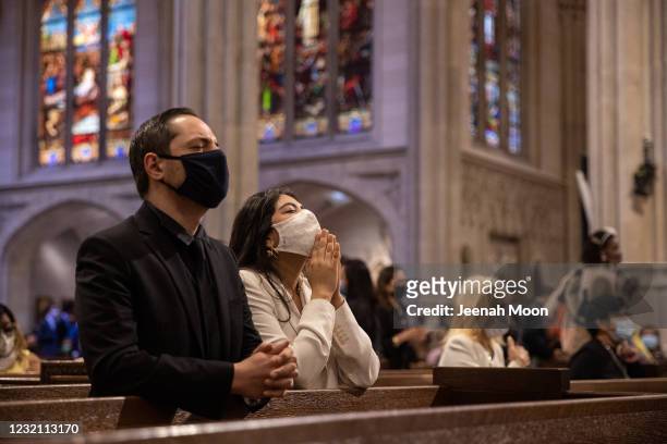 People wearing protective masks pray during a mass at Saint Patrick's Cathedral on April 4, 2021 in New York City. The annual Easter Parade and...