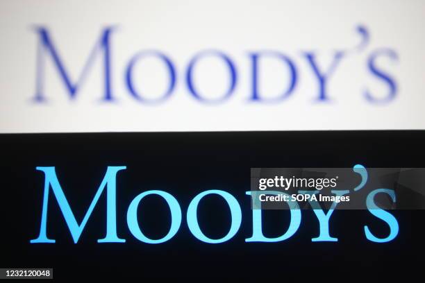 In this photo illustration the Moody's logo is seen on a smartphone and a pc screen.