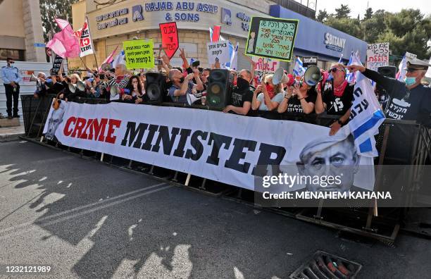 Protesters, one wearing a mask depicting Israeli Prime Minister Benjamin Netanyahu, gather during an anti-government demonstration outside the...