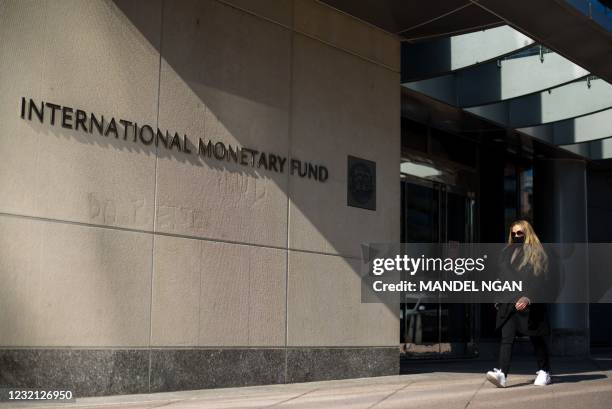 Woman walks past an International Monetary Fund headquarters building in Washington, DC on April 5, 2021. - The annual spring meetings of the...