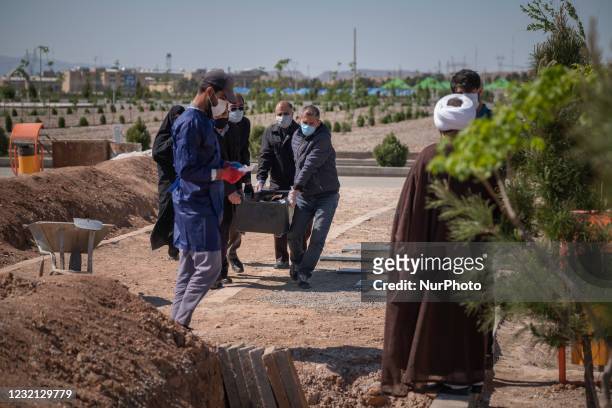 Relatives of a man who has died from coronavirus disease , carrying his dead body by a coffin in the Benhesht-e-Masoumeh cemetery in the holy city of...