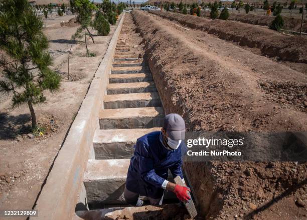 An Iranian cemetery worker covers a dead body of a man who has died from coronavirus disease, with rocks at a grave in the Benhesht-e-Masoumeh...