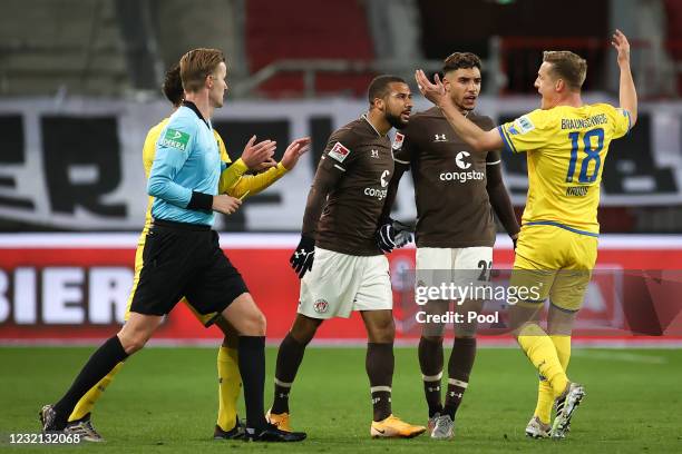 Rodrigo Zalazar and Daniel-Kofi Kyereh of St. Pauli argue with Felix Kroos of Braunschweig while referee Arne Aarnink holds a yellow card during the...