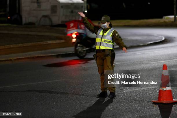 Police officer gestures during the curfew due to the coronavirus pandemic on April 5, 2021 in Santiago, Chile. The Andean country will close its...