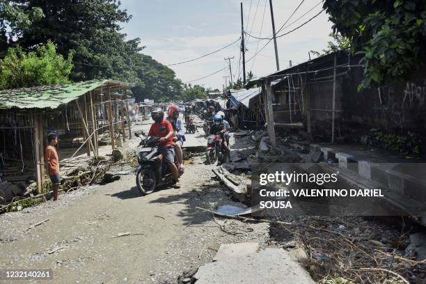 Residents make their way past damage along a street in Dili on April 6 after Tropical Cyclone Seroja battered the Southeast Asian nation, killing...