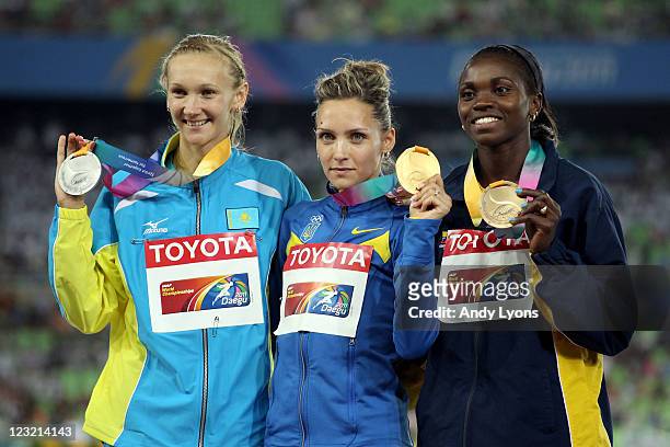 Olha Saladuha of Ukraine poses with the gold medal, Olga Rypakova of Kazakhstan the silver and Caterine Ibarguun of Colombia the bronze, following...