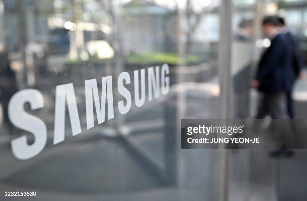 People walk past the logo of Samsung Electronics at the company's Seocho building in Seoul on April 7, 2021.
