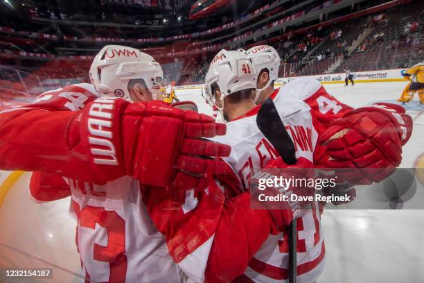 Jon Merrill, Luke Glendening and Darren Helm of the Detroit Red Wings congratulate teammate Adam Erne after he scores a goal during the third period...