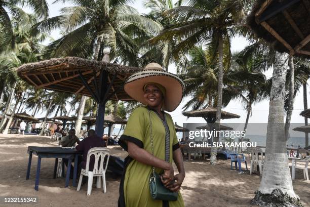 Hat vendor poses for a photograph on a beach in front of a hotel in Grand-Bassam, Ivory Coast, on March 28, 2021. - Five years after the jihadist...