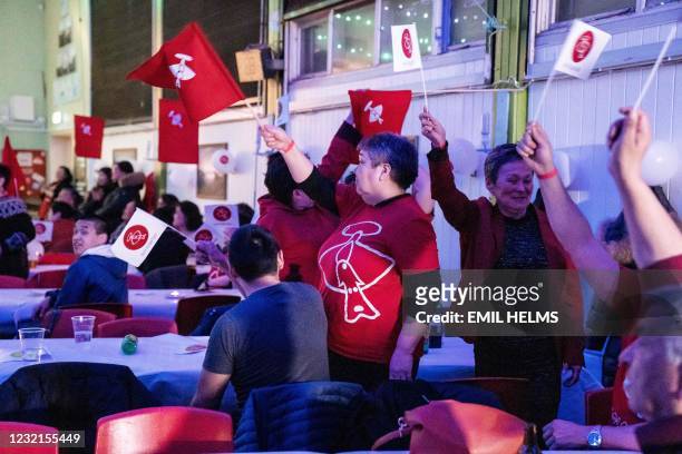 Members of the IA party wave party flags as they celebrate following the exit polls results of the legislative election in Nuuk, on April 6, 2021. -...