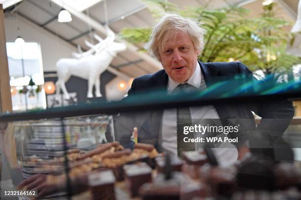 British Prime Minister Boris Johnson reacts as he looks at a display of cakes and desserts as he talks with business owners inside Lemon Street...