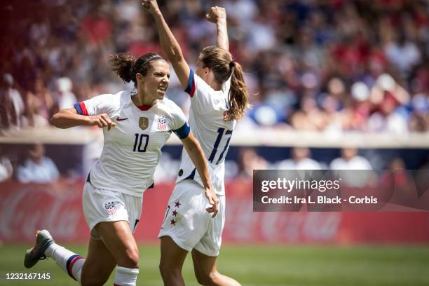 Captain Carli Lloyd of United States celebrates her goal while Tobin Heath of United States has her hands in the air and the Coca-Cola logo behind...