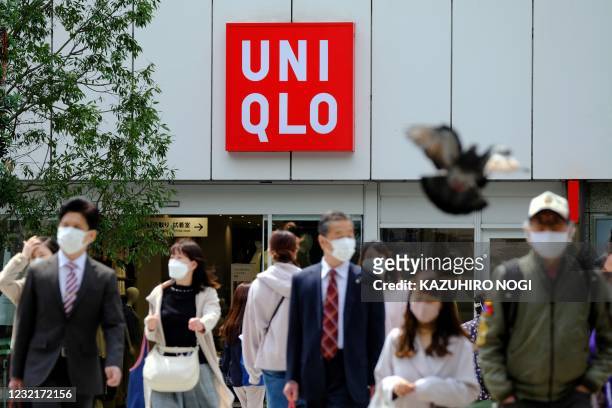 Pedestrians walk past a Uniqlo clothing store operated by Japan's Fast Retailing in Tokyo on April 8, 2021.