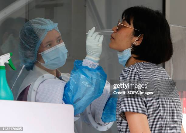 Health worker collects a nasal swab sample from a woman outside a nightclub in Bangkok. The Ministry of Public Health is set to recommend the closure...