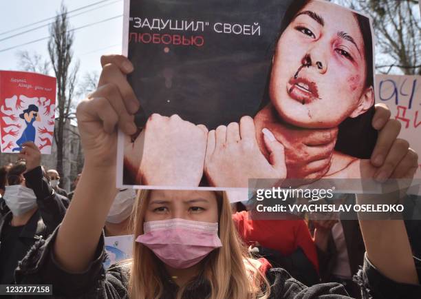 Woman holds a picture as she attends a rally for women's rights protection in Bishkek, on April 8, 2021. - Hundreds of people rallied in Kyrgyzstan's...