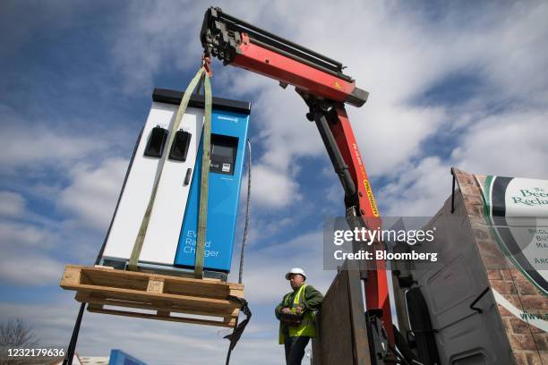 Worker uses a crane to lower a new Swarco AG electric vehicle rapid charger unit into position in Canterbury, U.K., on Thursday, April 8, 2021. Smart...