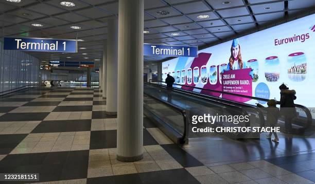 Passengers walk in a empty terminal of the Franz-Josef-Strauss airport in Munich, southern Germany, on April 8 amid the ongoing novel coronavirus...
