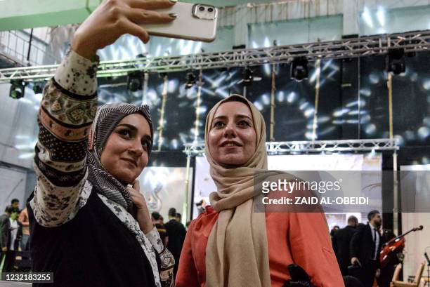 Women pose for a "selfie" photo on a phone after attending a performance by the "Watar" orchestral ensemble playing for the first time at the Spring...