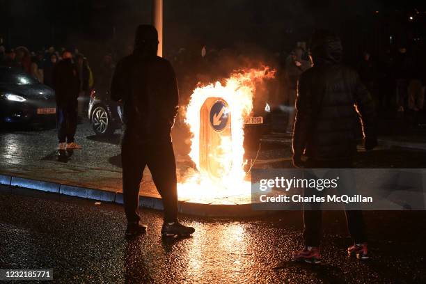 People watch a traffic sign burn as Nationalists attack police on Springfield Road just up from Peace Wall interface gates which divide the...