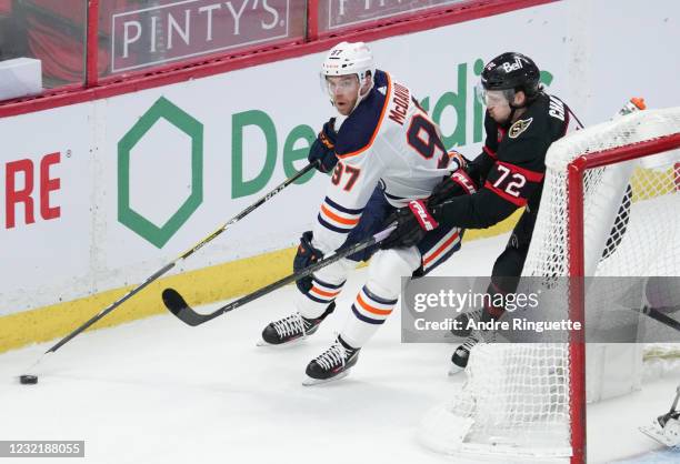Connor McDavid of the Edmonton Oilers controls the puck behind the net against Thomas Chabot of the Ottawa Senators at Canadian Tire Centre on April...