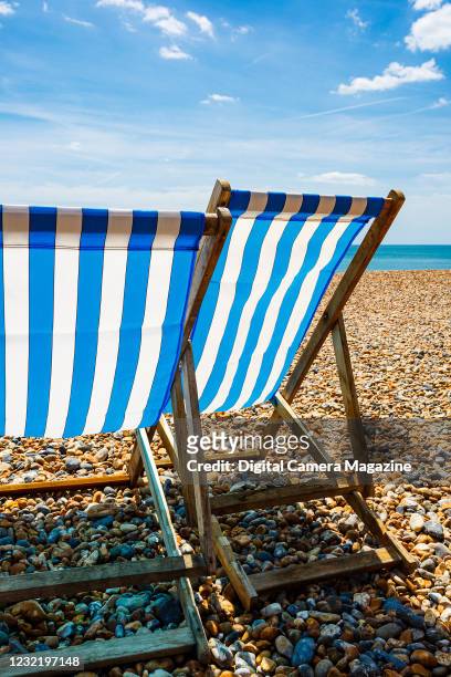 Blue and white striped deck chairs on a pebble beach in England, taken on June 21, 2018.