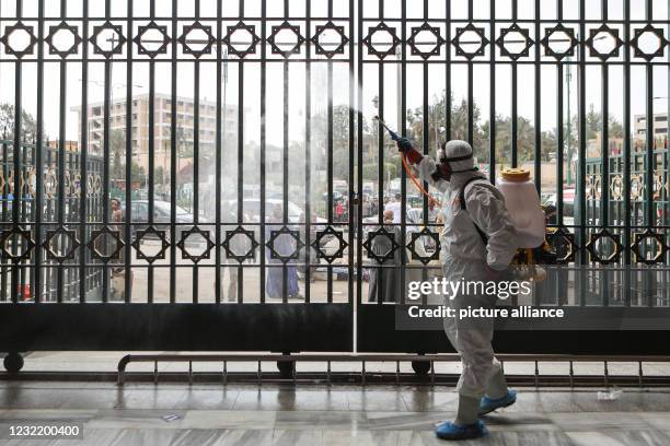 April 2021, Egypt, Cairo: A man in a hazmat suit takes part in the disinfection of Al-Sayeda Nafeesah Mosque to curb the spreading of coronavirus...