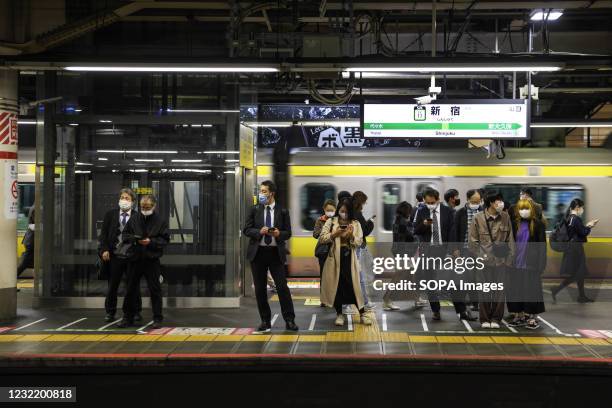 Passengers wearing face mask wait for a Yamanote-line train at Shinjuku Station.