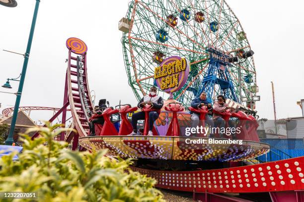 Visitors wear protective masks on the Electro Spin amusement ride at Luna Park in the Coney Island neighborhood in the Brooklyn borough of New York,...