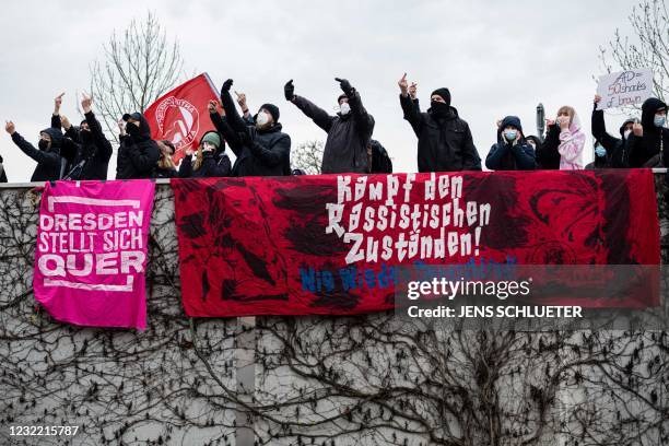 Protesters show their middle finger and display banners reading 'Fight racist conditions - Germany never again' and 'Dresden makes a stand' as they...