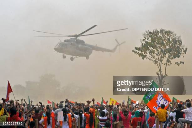 Supporters of Bharatiya Janata Party wave towards a helicopter carrying Indian Prime Minister Narendra Modi upon his arrival at a public rally during...