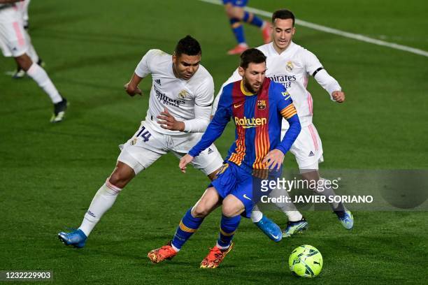 Real Madrid's Brazilian midfielder Casemiro and Real Madrid's Spanish forward Lucas Vazquez challenge Barcelona's Argentinian forward Lionel Messi...