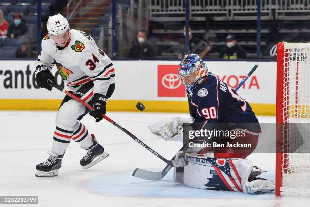 Goaltender Elvis Merzlikins of the Columbus Blue Jackets defends the net as Carl Soderberg of the Chicago Blackhawks follows a loose puck during the...