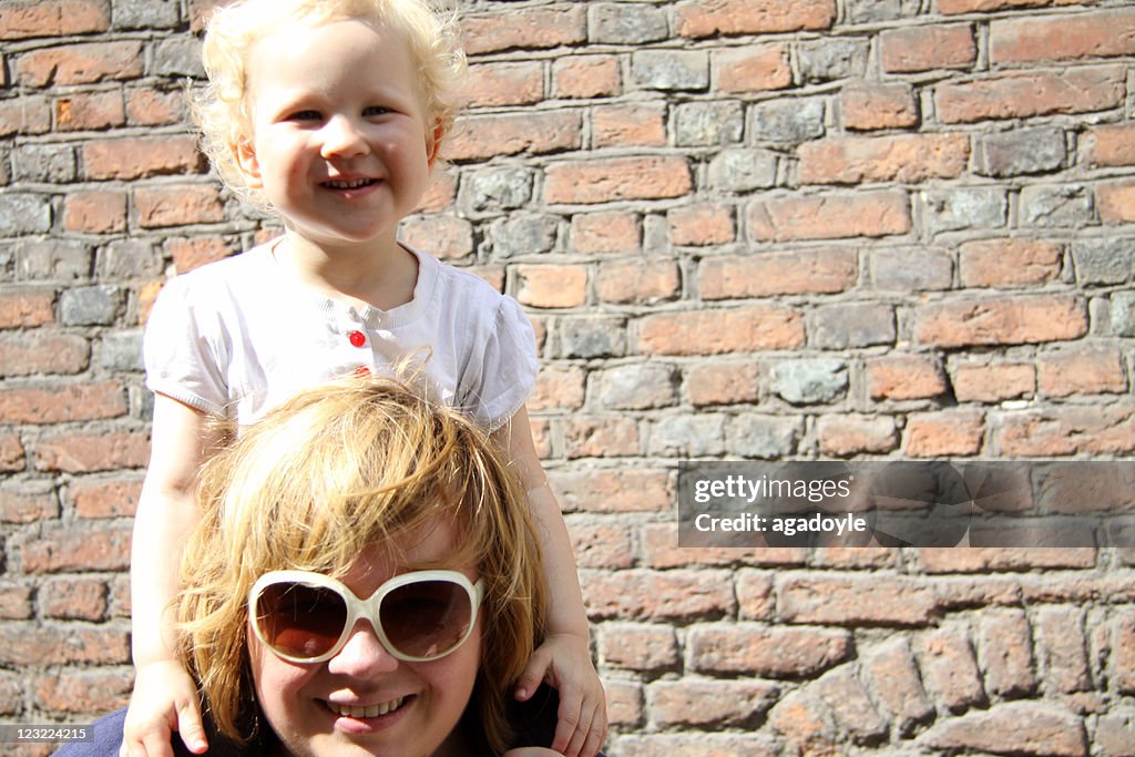 Mother holding her daughter on her shoulders