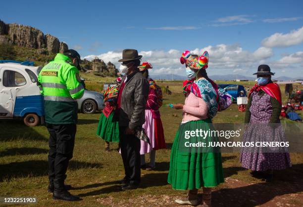 An policeman assists Quechua peasants arriving to vote in typical ethnic attires at a polling station in the remote rural village of Capachica, in...