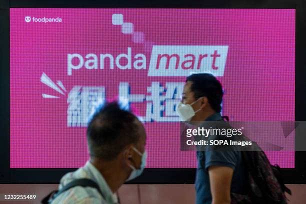 Commuters walk past a screen commercial ad of the the delivery take out food company, Foodpanda or Food Panda, at MTR subway station in Hong Kong.