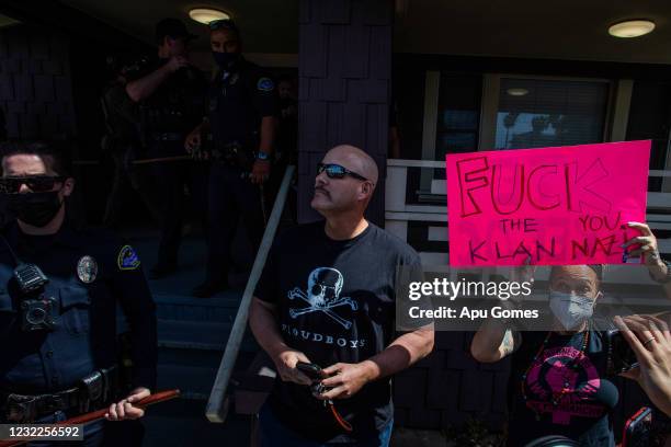 An unidentified man wearing a Proud Boys t-shirt stands in front of the Huntington Beach Police Station searching for police protection while people...