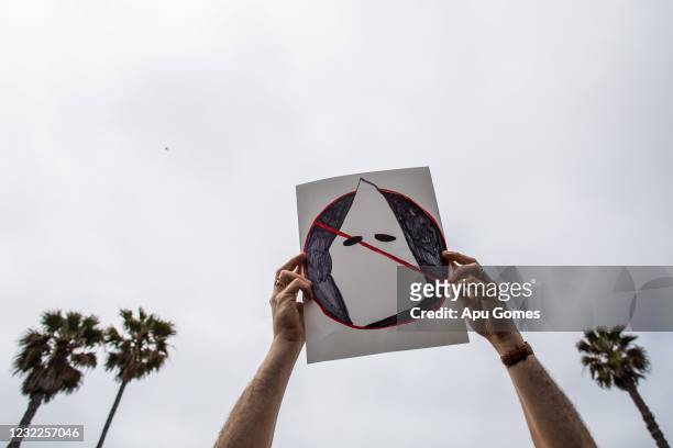 Joe Cook Gines holds an anti-Ku Klux Klan placard at Huntington Beach pier during a protest against white supremacy on April 11, 2021 in Huntington...